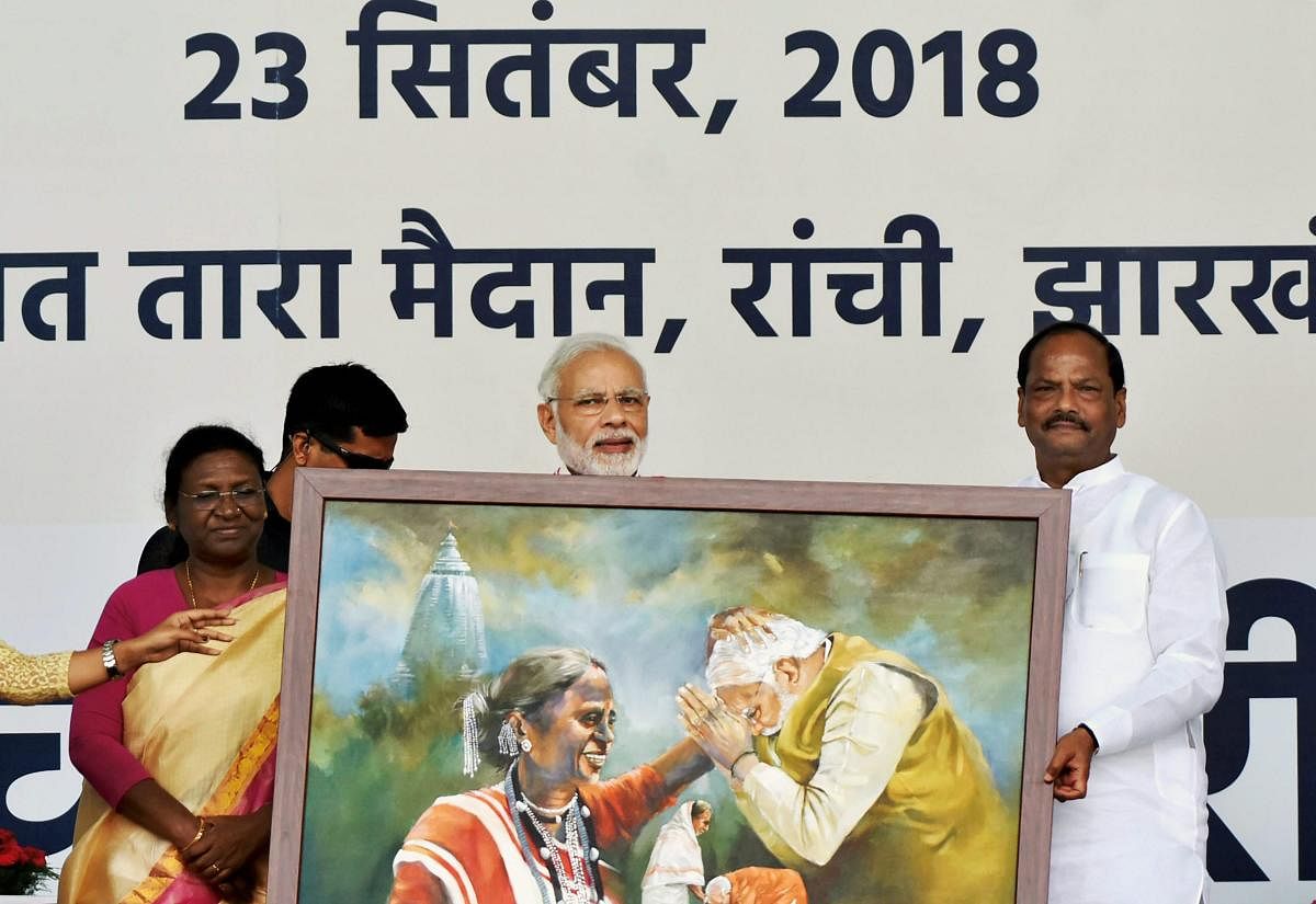 Prime Minister Narendra Modi being presented with a tribal art by Jharkhand Chief Minister Raghubar Das during the inauguration of 'Pradhan Mantri Jan Aarogya Yojna Ayushman Bharat Scheme', in Ranchi, Sunday, Sept 23, 2018. (PTI Photo)