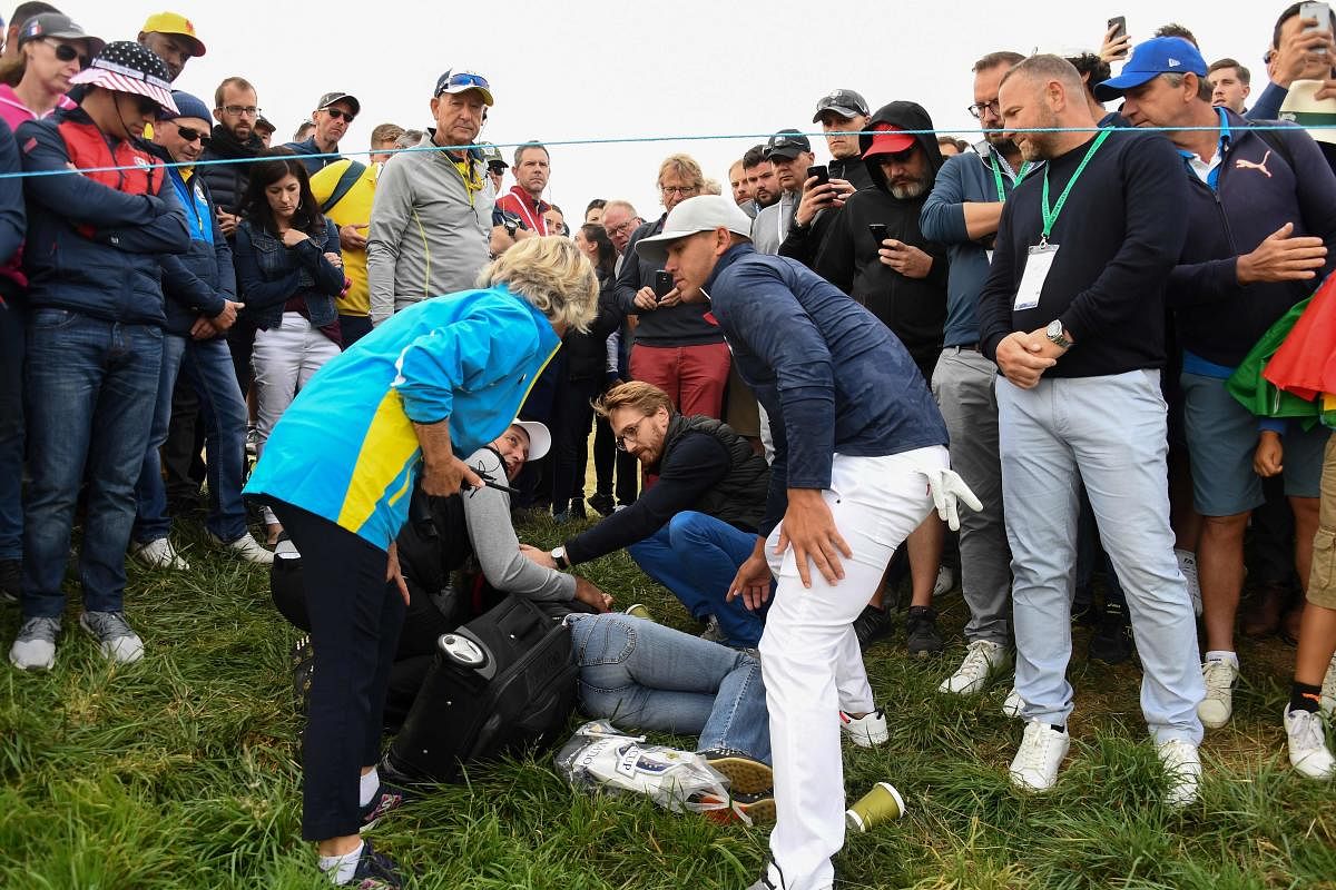 Brooks Koepka (right) checks on a woman after his wayward tee shot struck her on the face. AFP