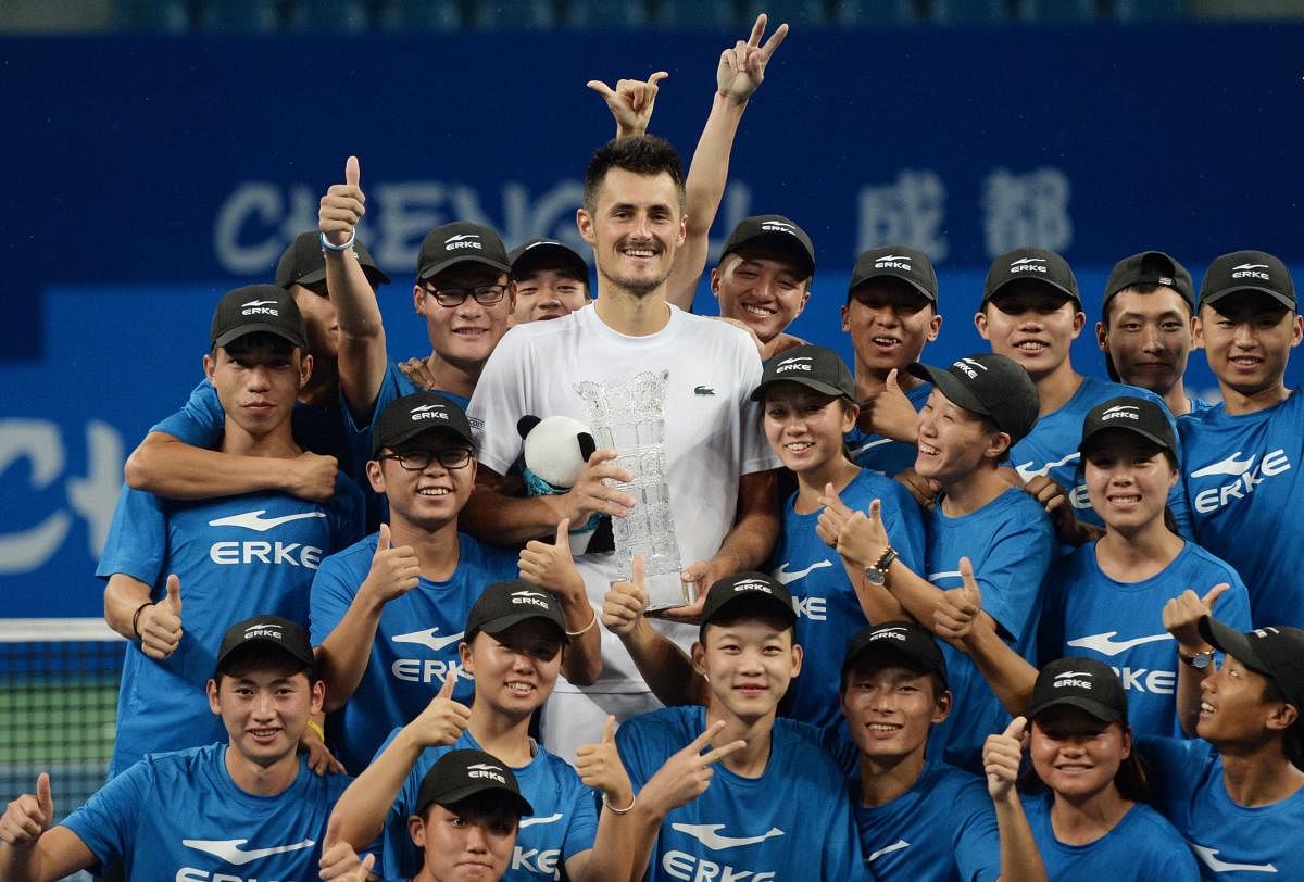 BACK ON TRACK Bernard Tomic of Australia celebrates his triumph at the ATP Chengdu Open with ball boys and girls in Chengdu on Sunday. AFP