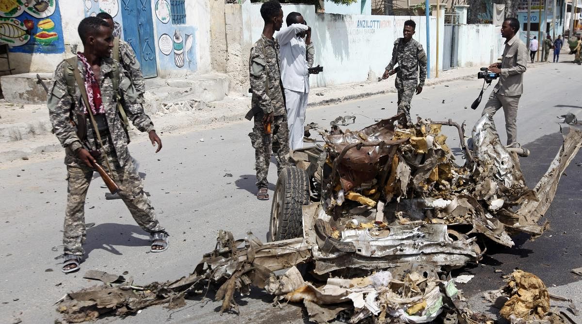 Soldiers look at the wreckage of a car bomb near the Somali presidential palace, in Mogadishu, Somali, on Saturday. AP/PTI