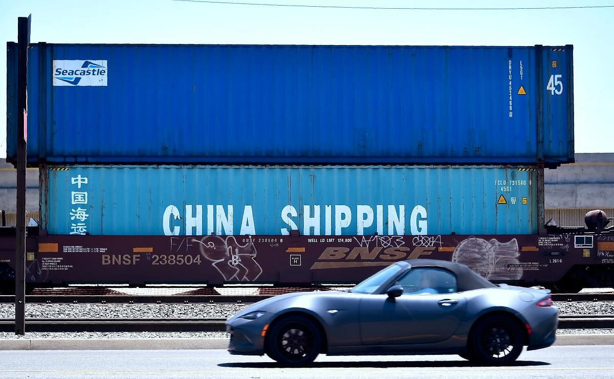 A motorist drives past shipping containers from China Shipping in at the Port of Long Beach in California on on July 12, 2018. AFP
