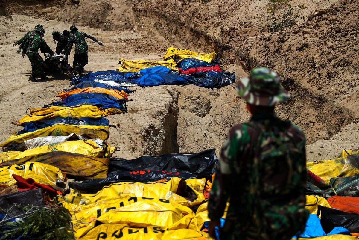 Soldiers move dead bodies of the victims of the earthquake and tsunami during a mass burial at the Poboya Cemetery in Palu, Central Sulawesi, Indonesia, October 2, 2018. (REUTERS)