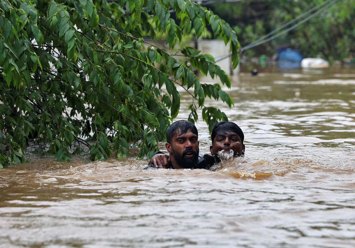A man rescues a drowning man from a flooded area after the opening of Idamalayr, Cheruthoni and Mullaperiyar dam shutters following heavy rains, on the outskirts of Kochi. Reuters photo