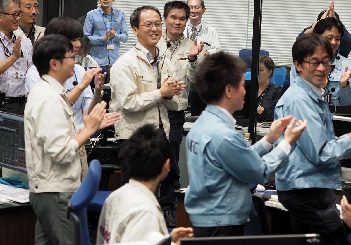 In this handout photograph taken and released by Institute of Space and Astronautical Science (ISAS) of Japan Aerospace Exploration Agency (JAXA) on October 3, 2018, researchers and employees applaud at a control room in Sagamihara, Kanagawa prefecture, d
