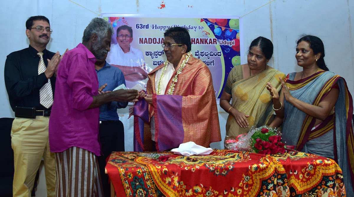 Nadoja awardee G Shankar presents a DD to a beneficiary at RAPCC Hall in the District Wenlock Hospital in Mangaluru on Thursday.