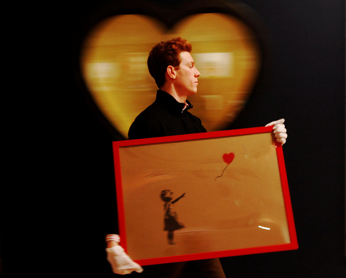 An employee walks with Banksy's "Girl and Balloon" 2009, at Bonhams auction house in London on March 23, 2012. Reuters