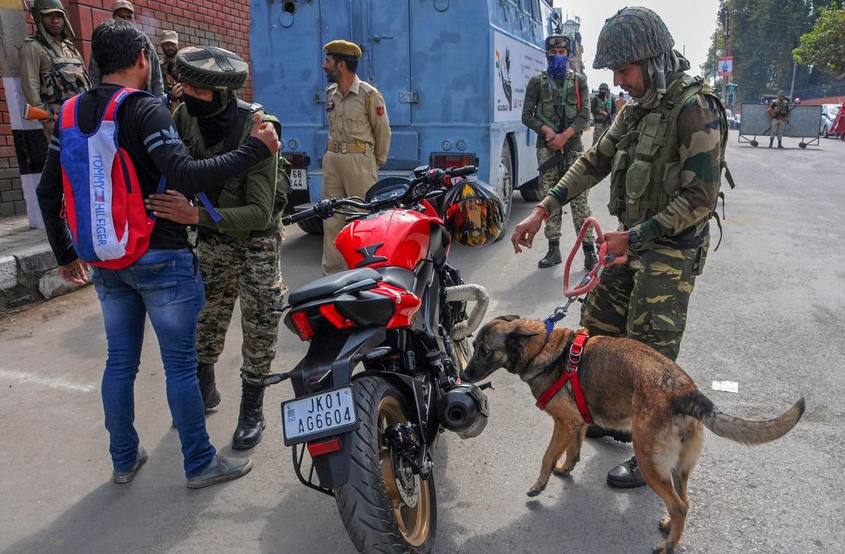 CRPF personnel check vehicles and motorcycles using sniffer dogs, ahead of polling for first phase of elections for urban local bodies in Kashmir, in Srinagar on Saturday. PTI