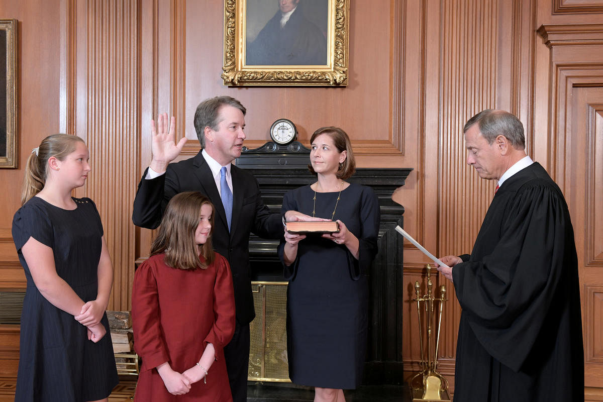 Judge Brett Kavanaugh is sworn in as an Associate Justice of the U.S. Supreme Court by Chief Justice John Roberts as Kavanaugh's wife Ashley holds the family bible and his daughters Liza and Margaret look on in a handout photo provided by the U.S. Supreme