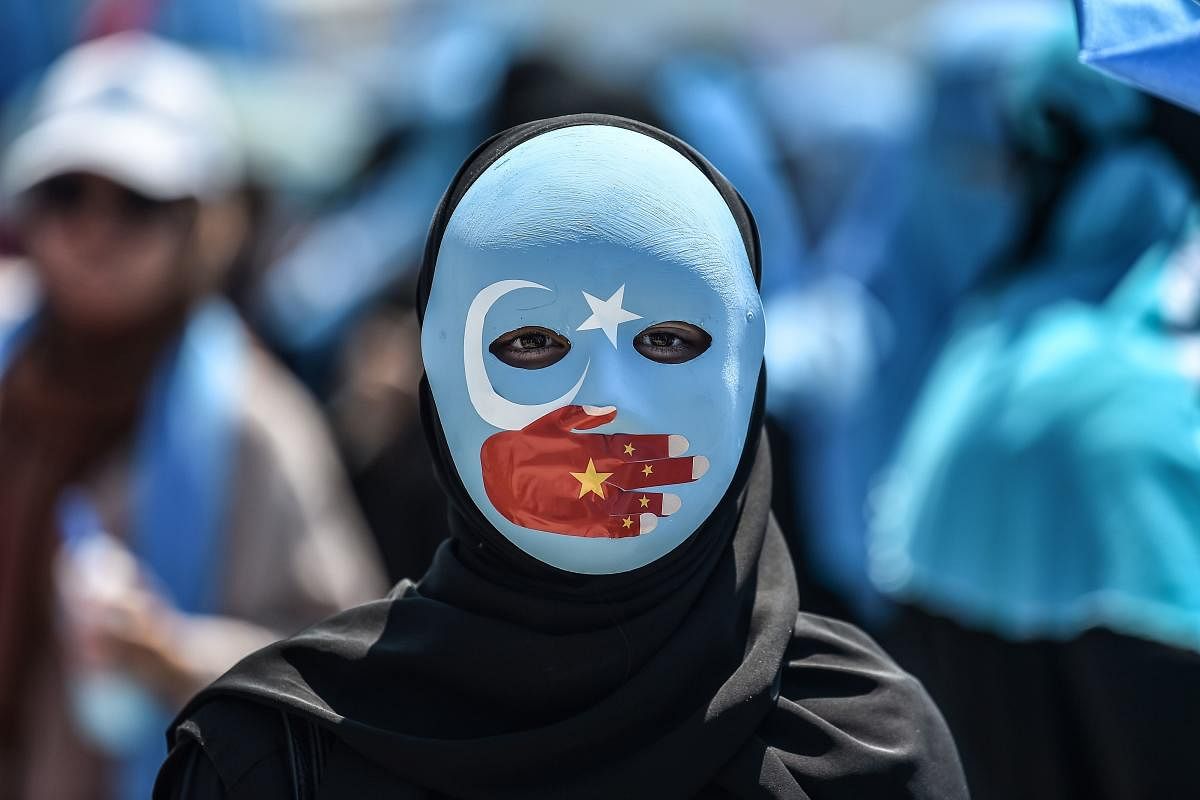 A demonstrator wearing a mask painted with the colours of the flag of East Turkestan and a hand bearing the colours of the Chinese flag attends a protest of supporters of the mostly Muslim Uighur minority and Turkish nationalists to denounce China's treat