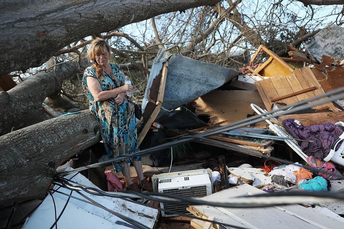 A woman stands among what is left of her home after Hurricane Michael destroyed it in Panama City, Florida, on October 11, 2018. She was inside her house when the tree fell crushing her house. AFP
