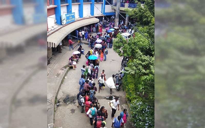 Students stand in a queue to collect their bus passes at the Kempegowda Bus Station in Bengaluru on Saturday. (DH Photo/Ranju P)