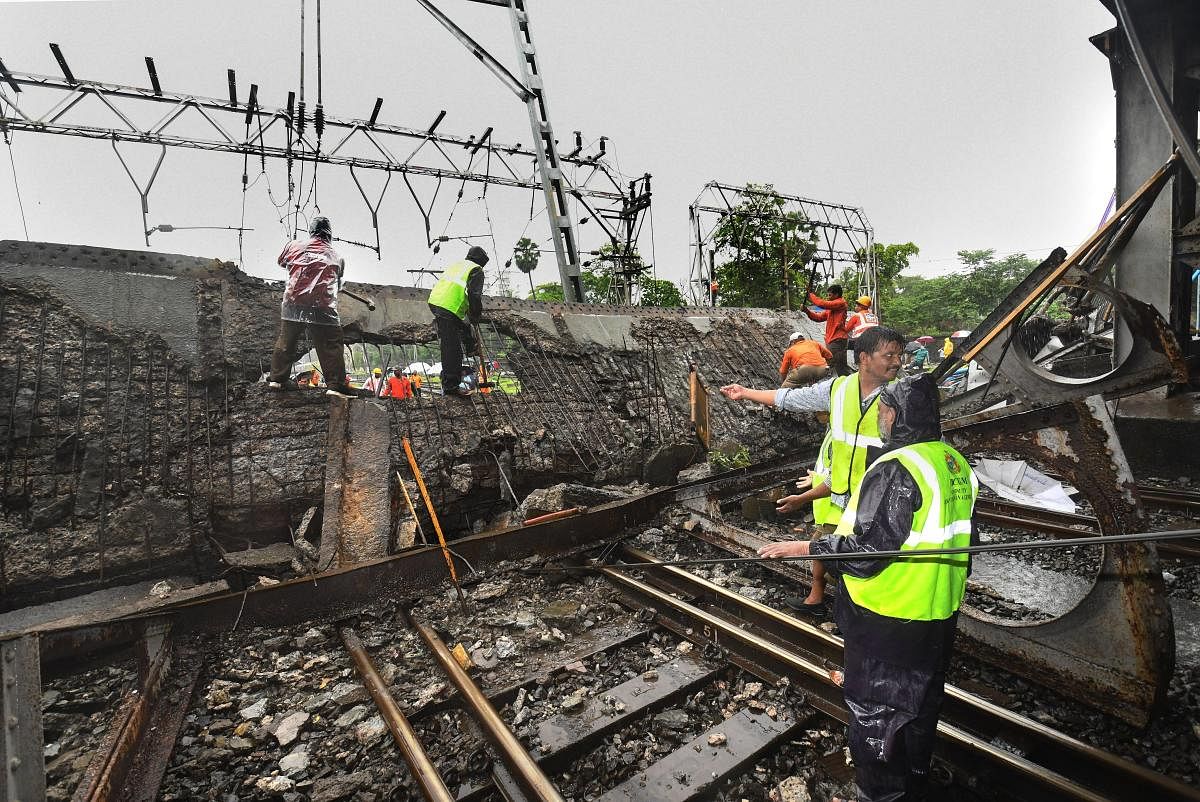 Rescue workers clear the debris of Gokhale foot overbridge that collapsed on the Western Railway tracks, at Andheri station following heavy rain, in Mumbai on Tuesday. PTI