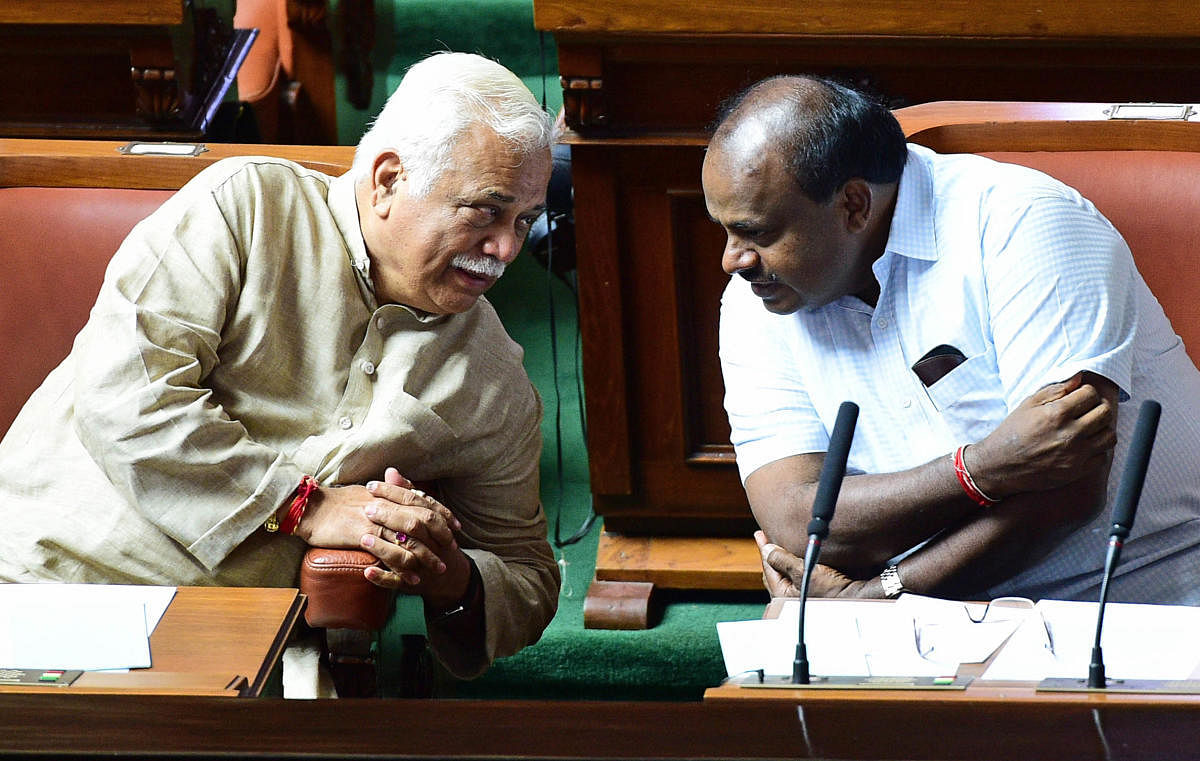 Revenue Minister R V Deshpande has a word with Chief Minister H D Kumaraswamy in the Assembly on Tuesday. DH Photo