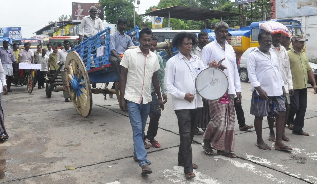 Udupi Zilla Nagarika Samithi stage a unique protest by pulling a cart in Udupi on Tuesday.