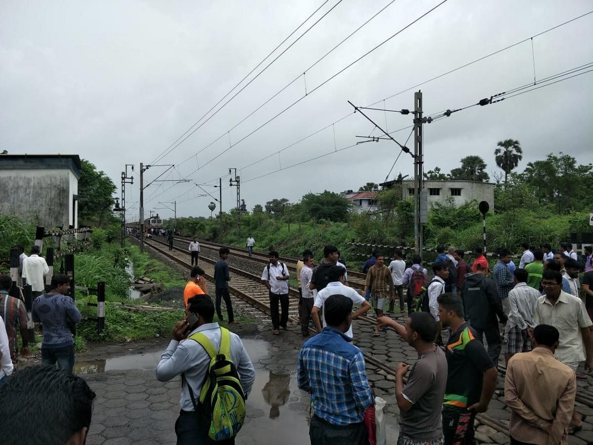 Commuters block the track while waiting for a train near Umroli station, in the Palghar district of Maharashtra on Wednesday.