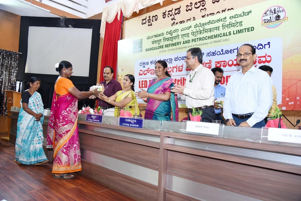 ZP President Meenakshi Shanthigodu distributes LED bulbs to a beneficiary at a programme organised at the Zilla Panchayat Auditorium in Mangaluru on Friday.