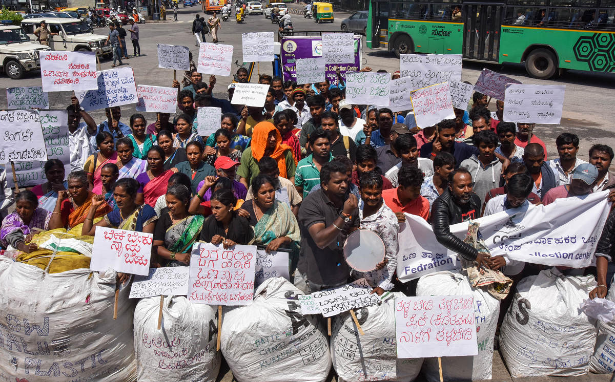 Workers of the dry waste collection centres stage a protest over pending wages outside Town Hall on Saturday. DH Photo