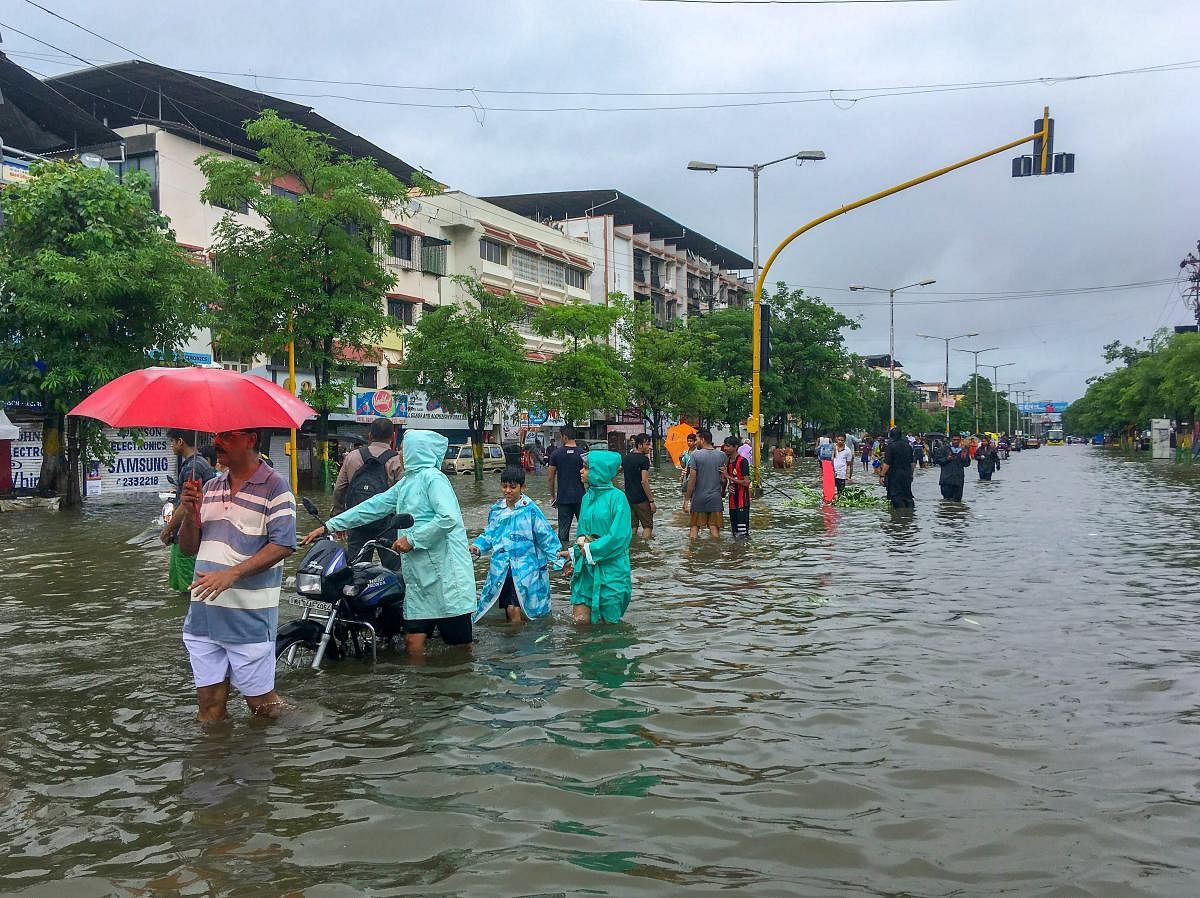 People wade through a flooded street following heavy rains, in Vasai, Maharashtra on Tuesday, 10 July, 2018. (PTI Photo) 