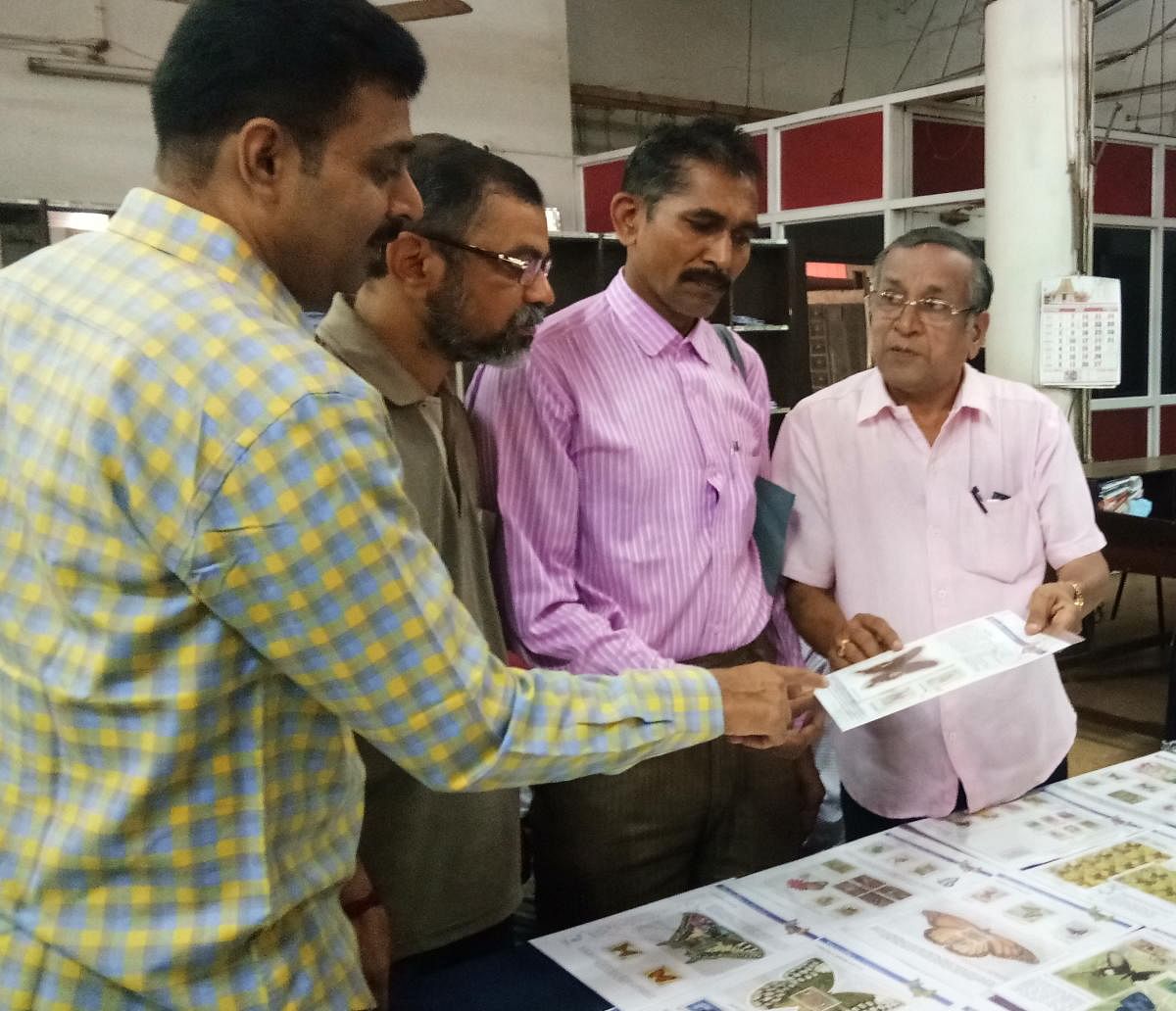 Baikady Shrinivas Rao (extreme right), explains his collection to the visitors during the philatelic exhibition at the head post office in Pandeshwara, Mangaluru, on Sunday.