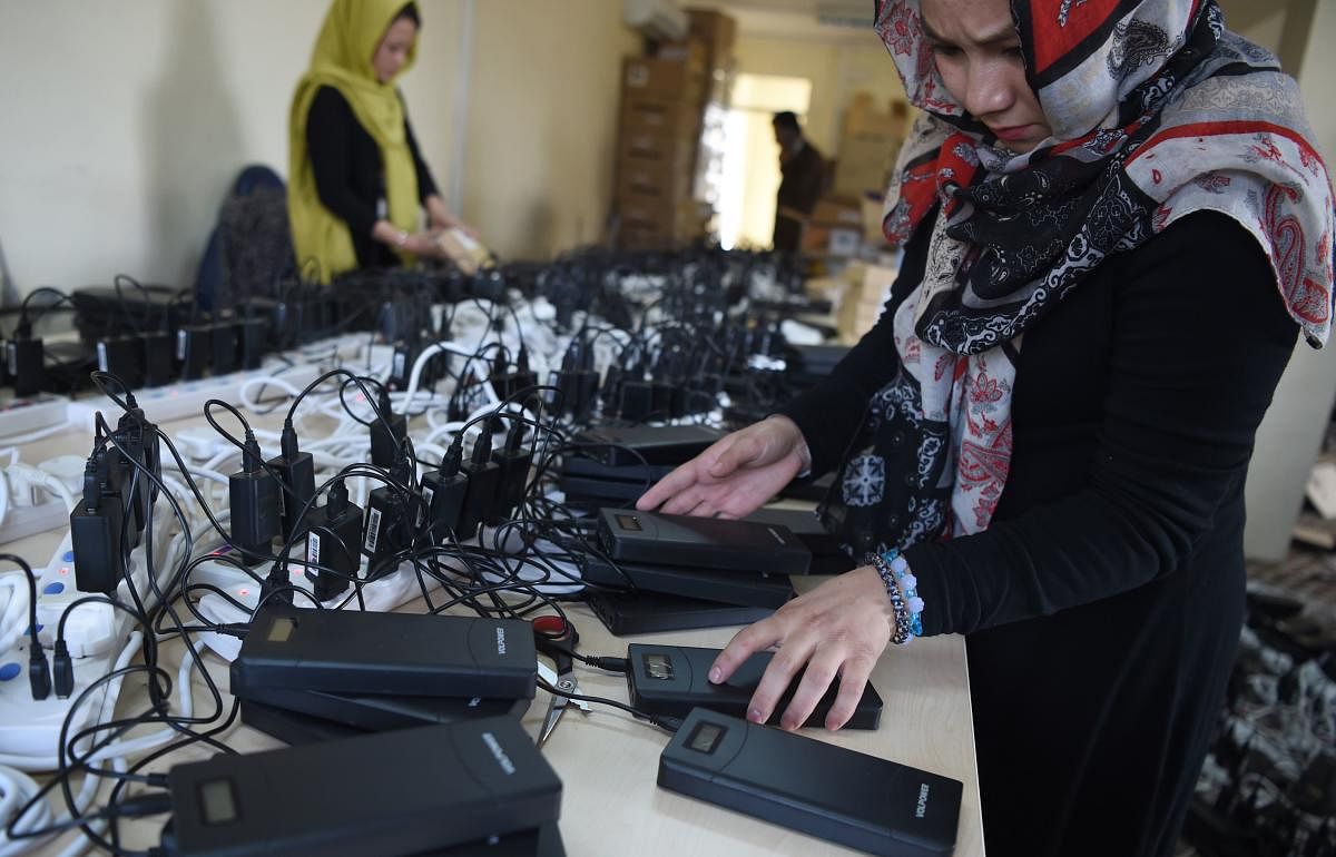 Afghan employees of the Independent Election Commission (IEC) charges power bank devices at a warehouse in Kabul. (AFP file photo)