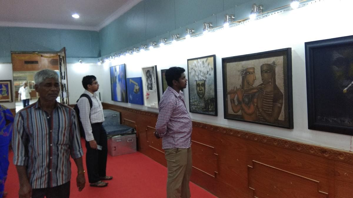 Visitors view paintings during Dasara Art Exhibition at Suchitra Art Gallery on Kalamandira premises in Mysuru on Monday. DH PHOTO