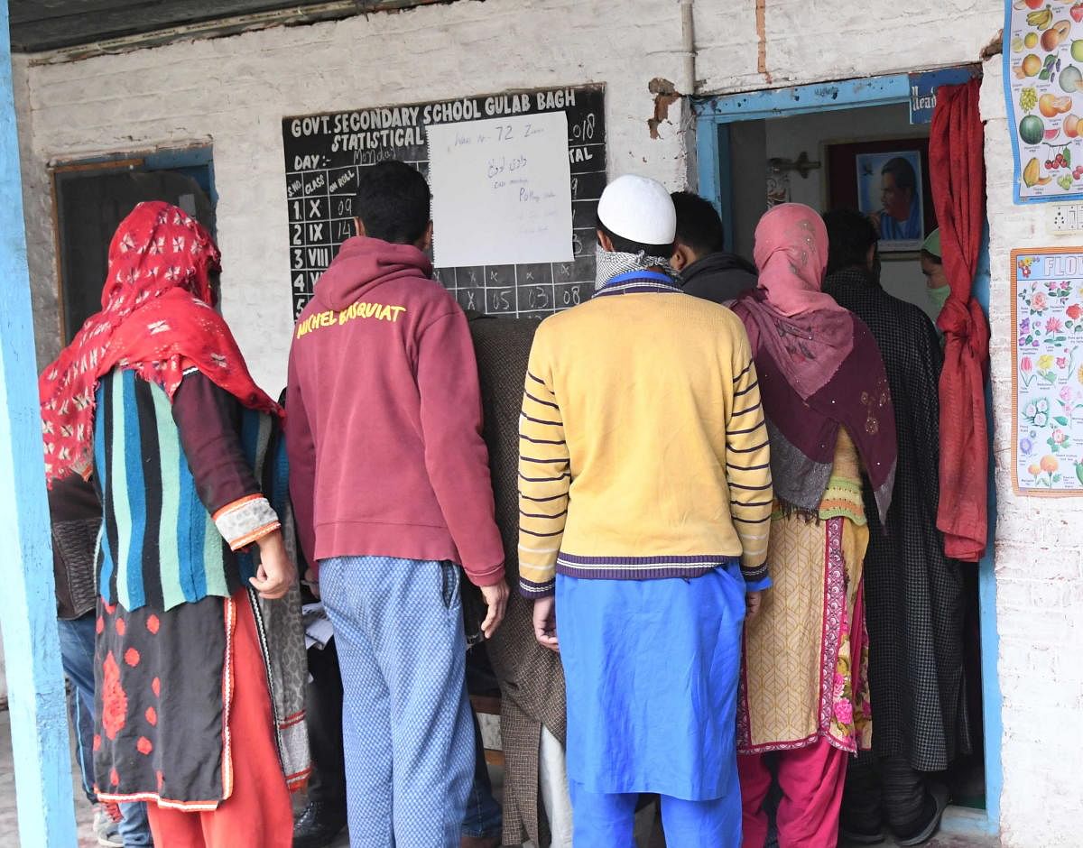 People wait in a queue to cast their vote at a polling station during the fourth phase of municipal elections at Gulab Bagh Zakura in Srinagar on Tuesday. DH photo / Umer Asif