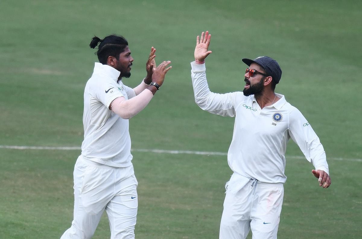 Indian captain Virat Kohli and bowler Umesh Yadav celebrate the dismissal of Roston Chase during the third day's play of the second Test cricket match between India and West Indies at the Rajiv Gandhi International Cricket Stadium in Hyderabad on October