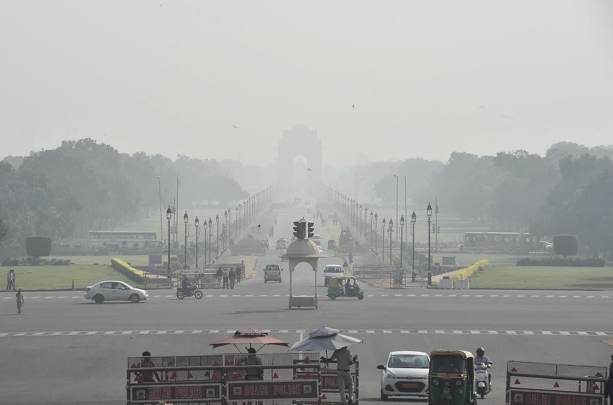 Vehicles ply on Rajpath as a thick smog engulfs India Gate in New Delhi. (PTI Photo)