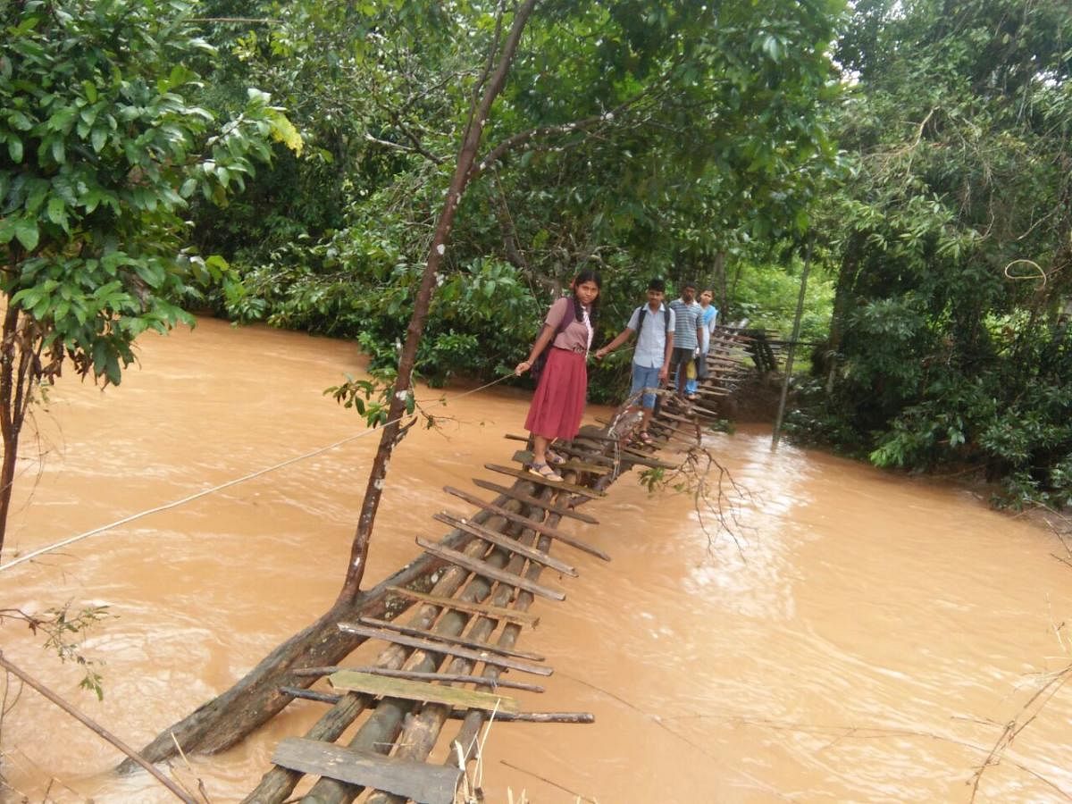 Students cross Brahmi stream, on a makeshift footbridge at Matagaru in Kelakuli village in Koppa taluk.