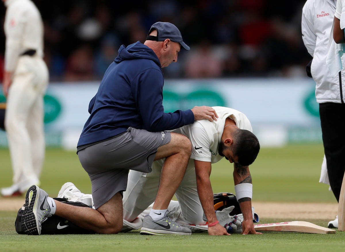 Indian captain Virat Kohli receives treatment from medical staff for a back injury. Reuters