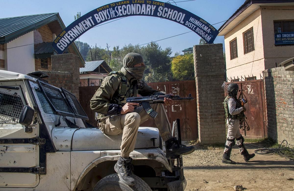 Security personnel stand guard at a polling station during the first phase of elections for urban local bodies, at Humhama in Budgam district of central Kashmir, Monday, October 8, 2018. (PTI File Photo/S Irfan)