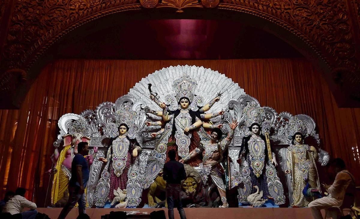 Artists give finishing touches to idols of deities at a Durga Puja pandal, in Kolkata, on Thursday. PTI