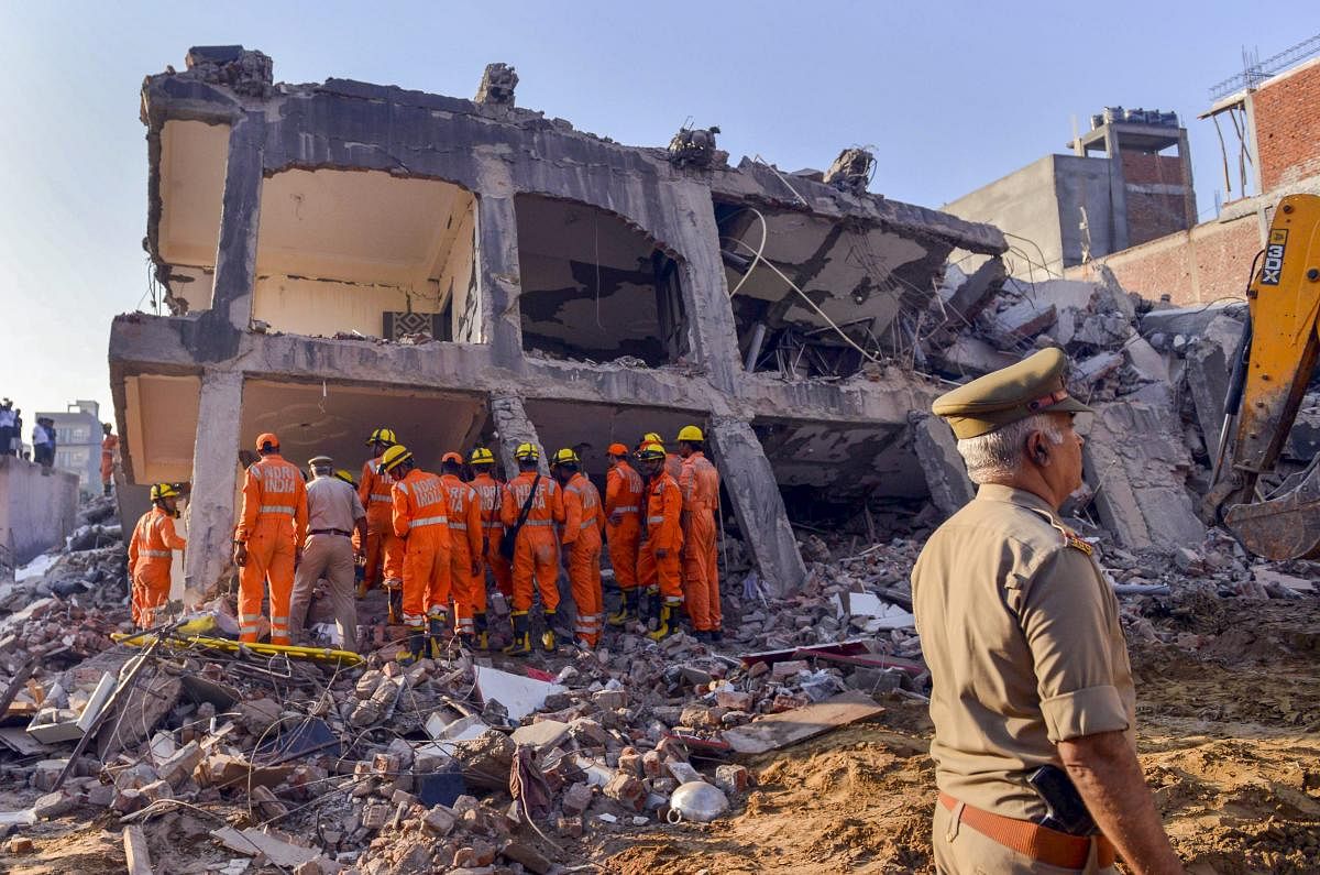 Rescue workers search for survivors under the debris of a collapsed building at Shahberi village, in Greater Noida West on Wednesday, July 18, 2018. A six-storey under-construction building collapsed in Greater Noida, killing at least two persons and trapping several others under the debris. (PTI Photo)
