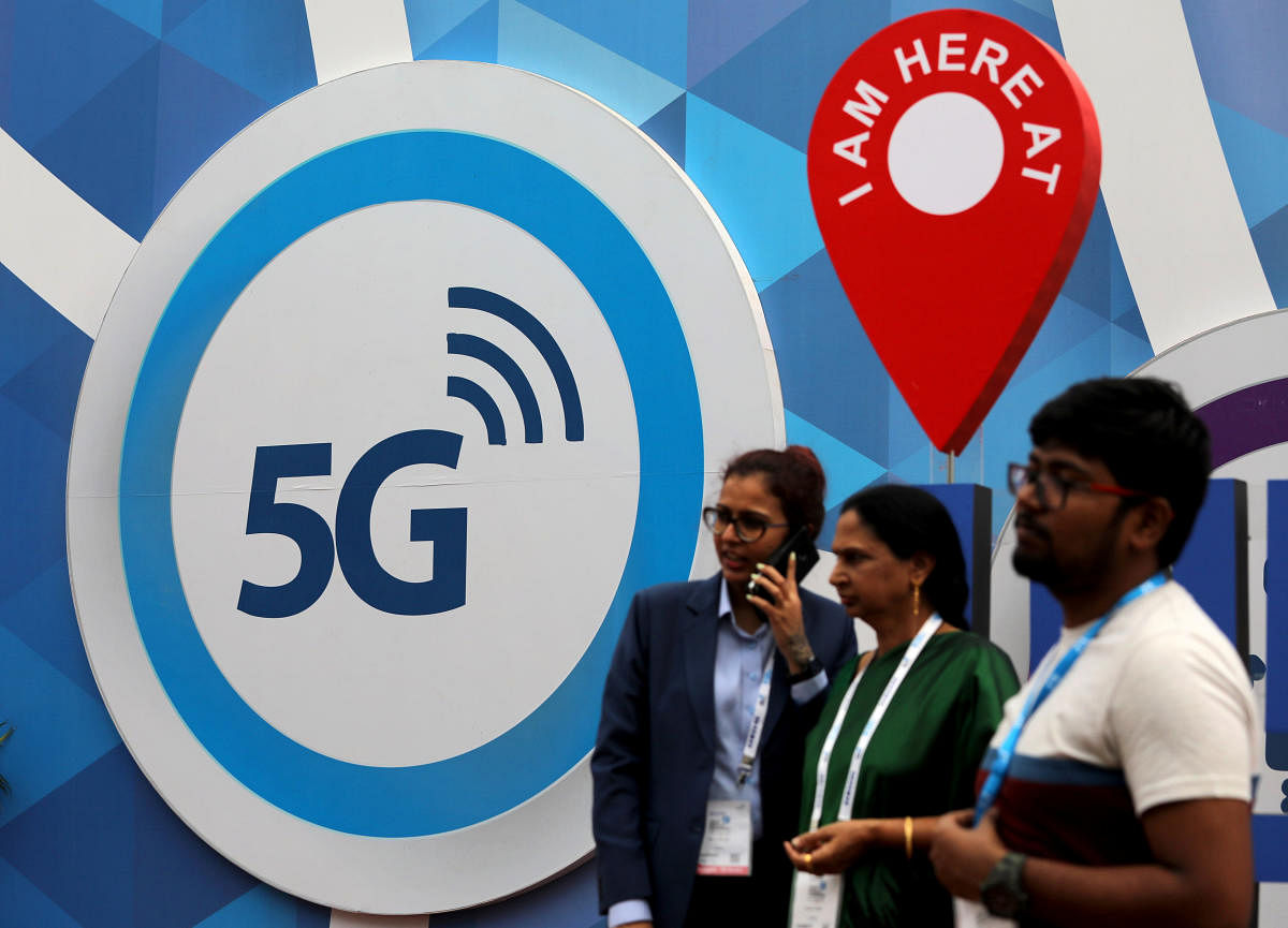 People stand in front of a board depicting 5G network at the India Mobile Congress 2018 in New Delhi on Friday. REUTERS