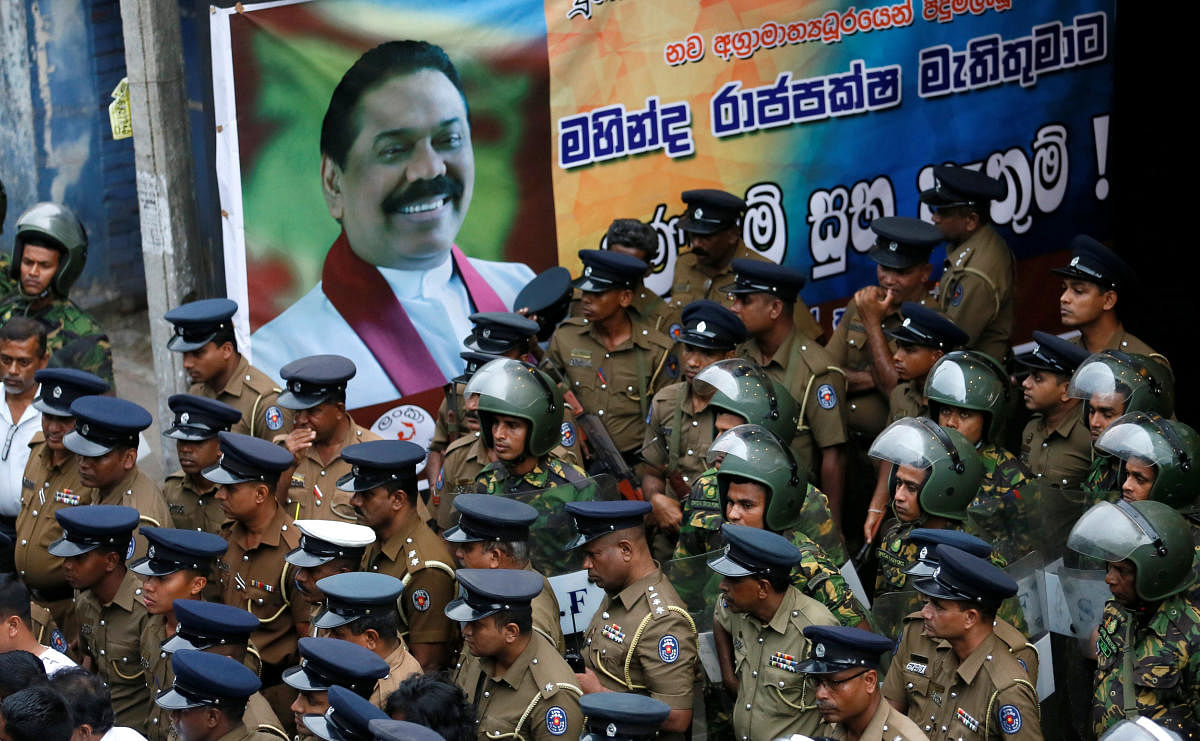 Members of Sri Lanka's Special Task Force and the police stand guard next to a poster of newly appointed Prime Minister Mahinda Rajapaksa after an official security guard of sacked minister Arjuna Ranatunga shot and wounded three people in front of the Ceylon Petroleum Corporation, in Colombo, Sri Lanka October 28, 2018. REUTERS