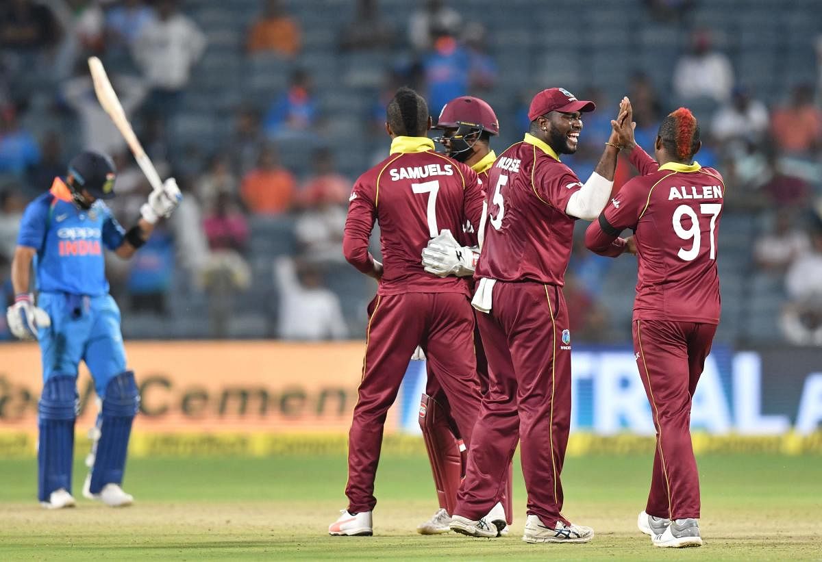 West Indies players celebrate after the wicket of India captain Virat Kohli during the third one day international (ODI) cricket match between India and West Indies at the Maharashtra Cricket Association Stadium in Pune on October 27, 2018. (Photo by PUNI