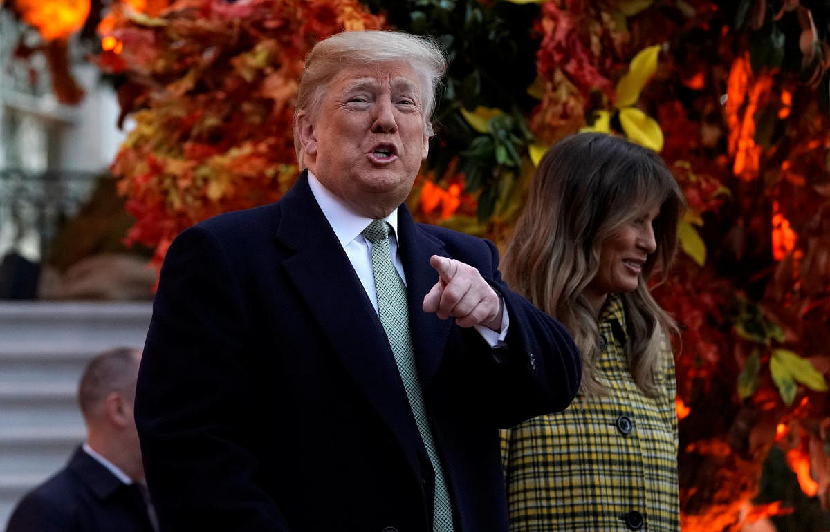 US President Donald Trump points to waiting parents as he and U.S. first lady Melania Trump hand out Halloween candy to trick-or-treaters at the White House in Washington, October 28, 2018. (REUTERS)