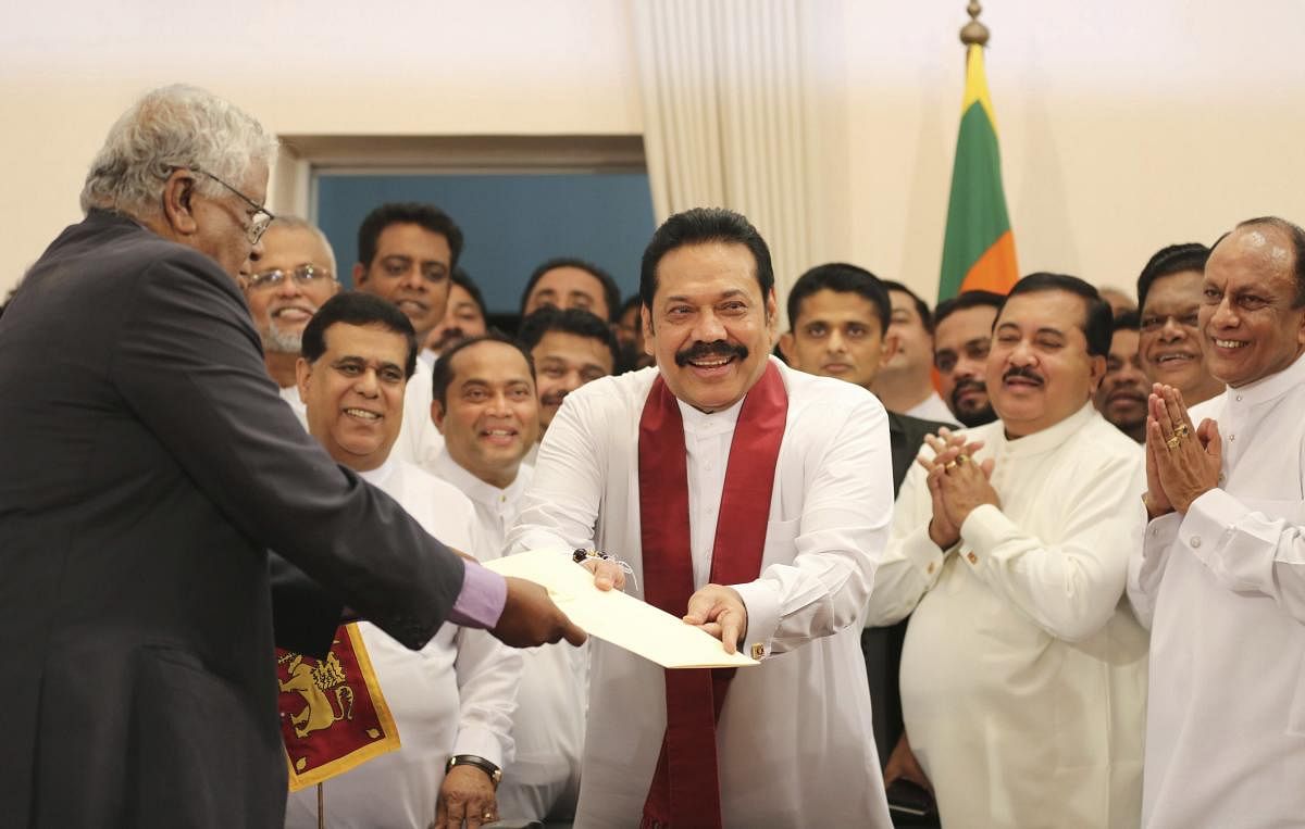 Sri Lanka's newly appointed prime minister Mahinda Rajapaksa, center, hands over inaugural documents to an official during his duties assuming ceremony in Colombo, Sri Lanka, Monday, Oct. 29, 2018. AP/PTI