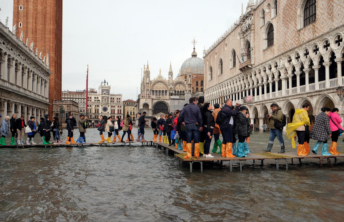 People walk on a catwalk in a flooded Saint Mark Square during a period of seasonal high water in Venice, Italy October 29, 2018. (Reuters)