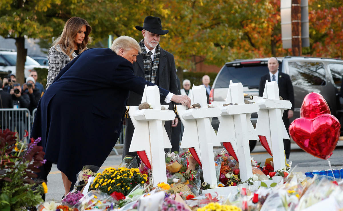 US President Donald Trump places a stone as he stands with first lady Melania Trump and Tree of Life Synagogue Rabbi Jeffrey Myers at a makeshift memorial to the victims outside the synagogue where a gunman killed eleven people and wounded six during a mass shooting in Pittsburgh, Pennsylvania, October 30, 2018. (REUTERS)