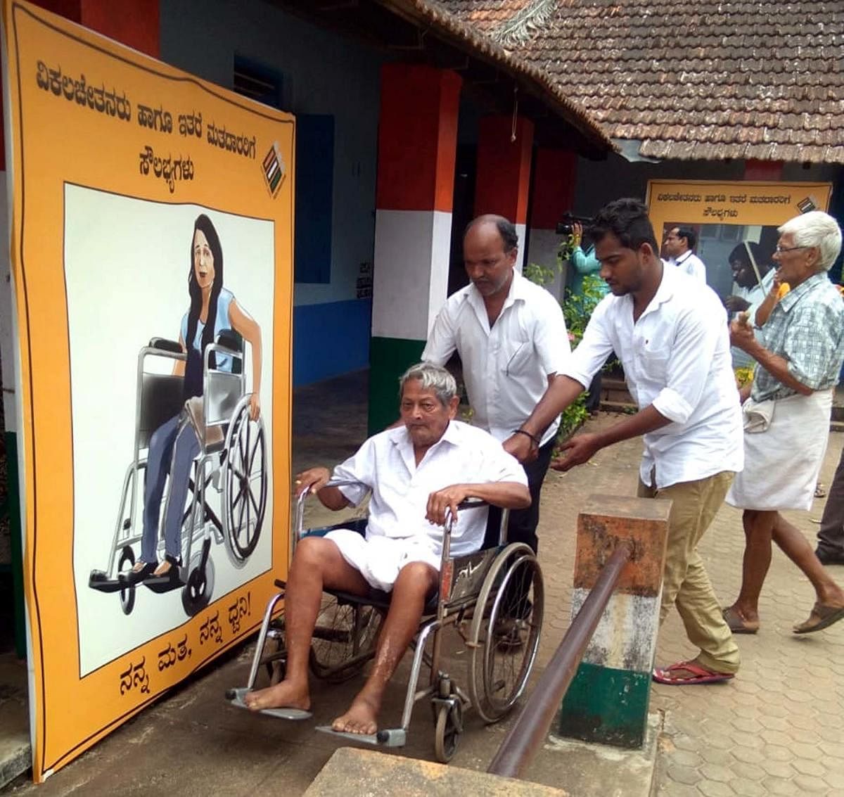 A physically challenged voter is being offered a wheelchair at a polling booth in Byndoor.