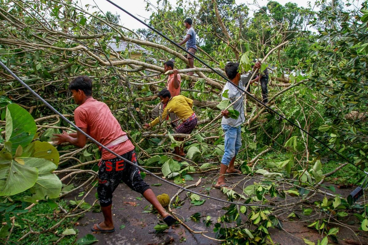 Residents try to clear the road after a cyclone hit Belchharra village at Khowai district of Tripura on Monday. PTI Photo