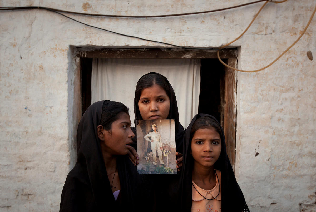 The daughters of Pakistani Christian woman Asia Bibi pose with an image of their mother while standing outside their residence in Sheikhupura Pakistan. Reuters file photo