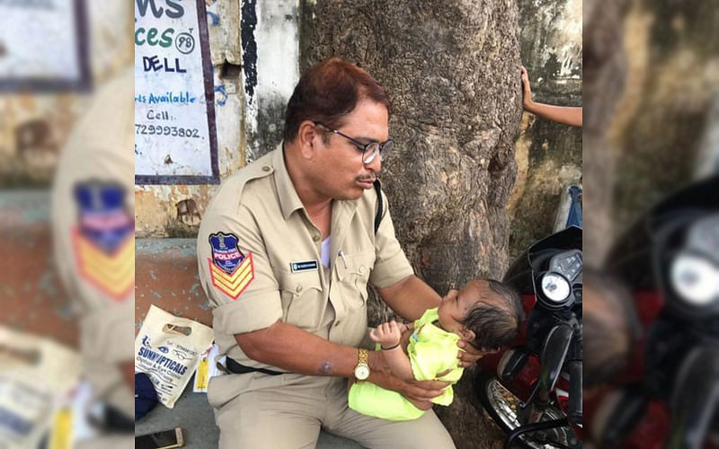 Telangana cop Mujeeb Ur Rehman with the toddler outside the examination centre. (DH Photo)