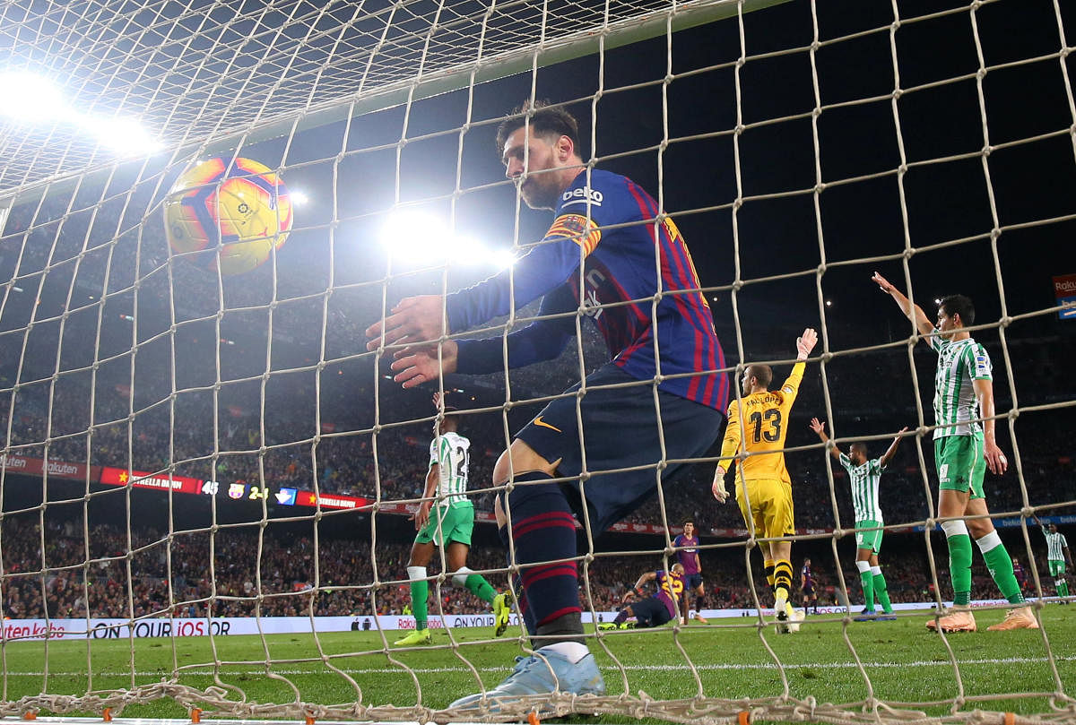 Barcelona's Lionel Messi collects the ball from the goal net after scoring their third goal against Real Betis on Sunday. (REUTERS)