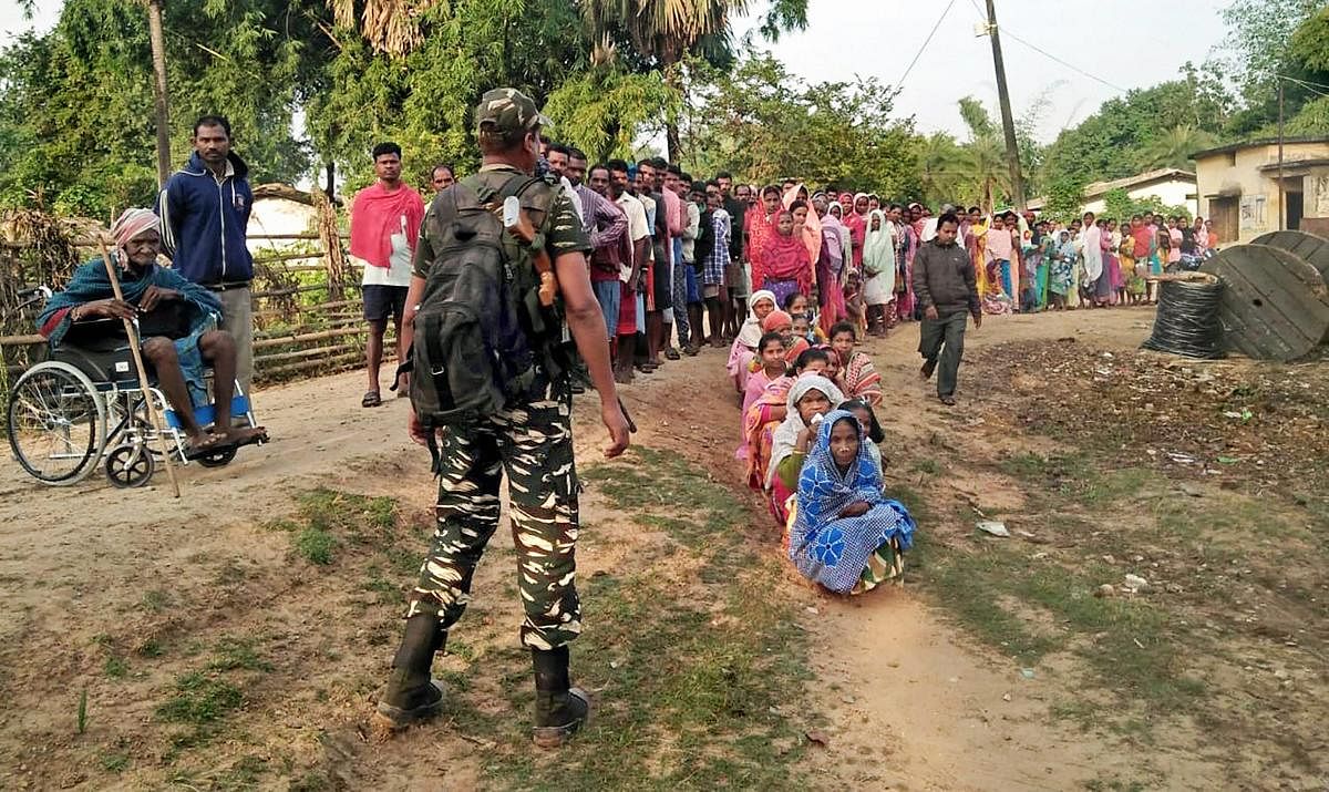 People wait to cast votes at a polling station in the Maoist-hit Sukma district on Monday. PTI