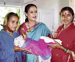 Dr Sudha Kankaria with two women holding their children.