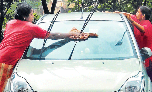 Two women clean a car in Technopark in Thiruvananthapuram.