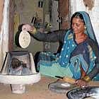 A happy village woman making chappatis on stove powered by solar energy