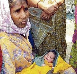 A woman holding a new born baby left in a cradle